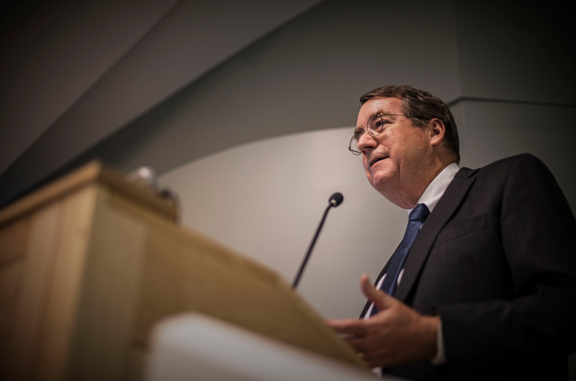 A research doctor speaks behind a podium to Airmen inside an auditorium.