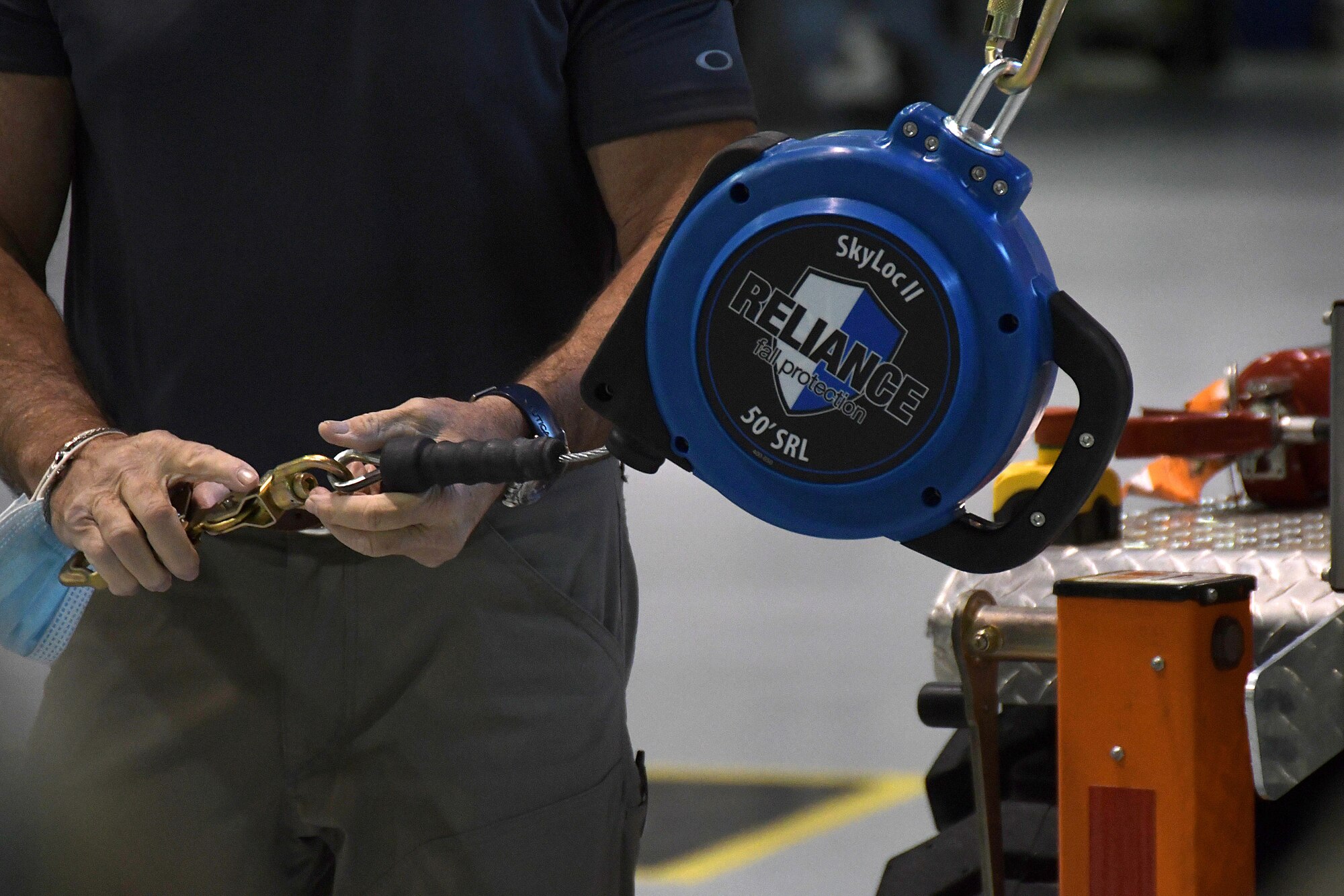 A contractor demonstrates how the self-retracting lifeline (SRL) works on the new fall protection system during a training session at Dobbins Air Reserve Base, Georgia, Oct. 16, 2020.  In the event of a fall, the SRL locks in place, much like a seatbelt in a car, and prevents them from hitting the ground. The 94th Aircraft Maintenance Squadron recently acquired several mobile fall protection systems to improve the safety of maintainers and operators as they perform their duties on the aircraft. (U.S. Air Force photo/Andrew Park)