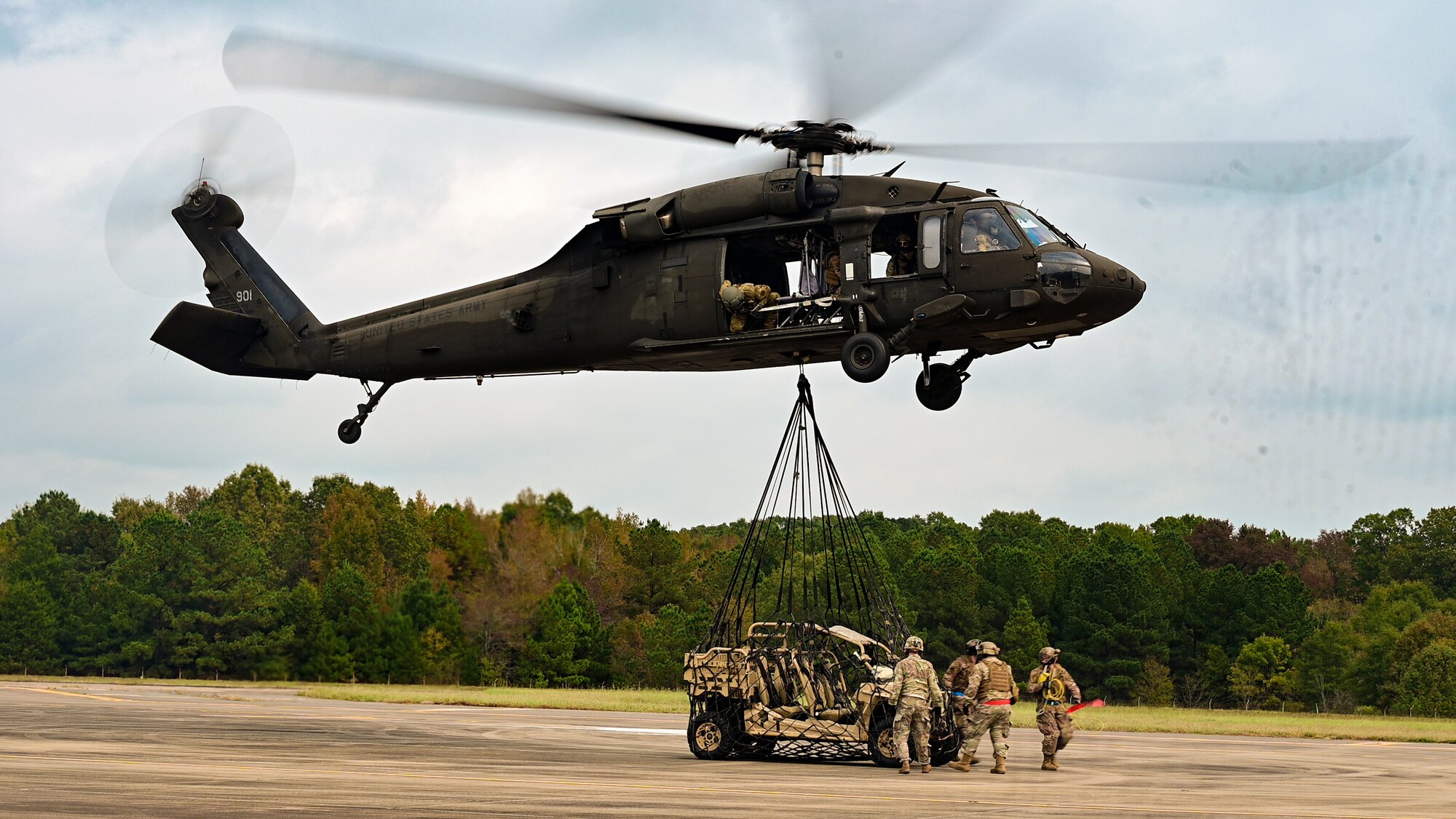 An off-road vehicle is attached to a helicopter for transport.
