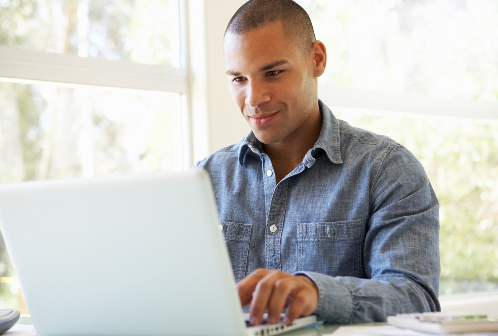 Young Man Using Laptop At Home Looking At The Screen