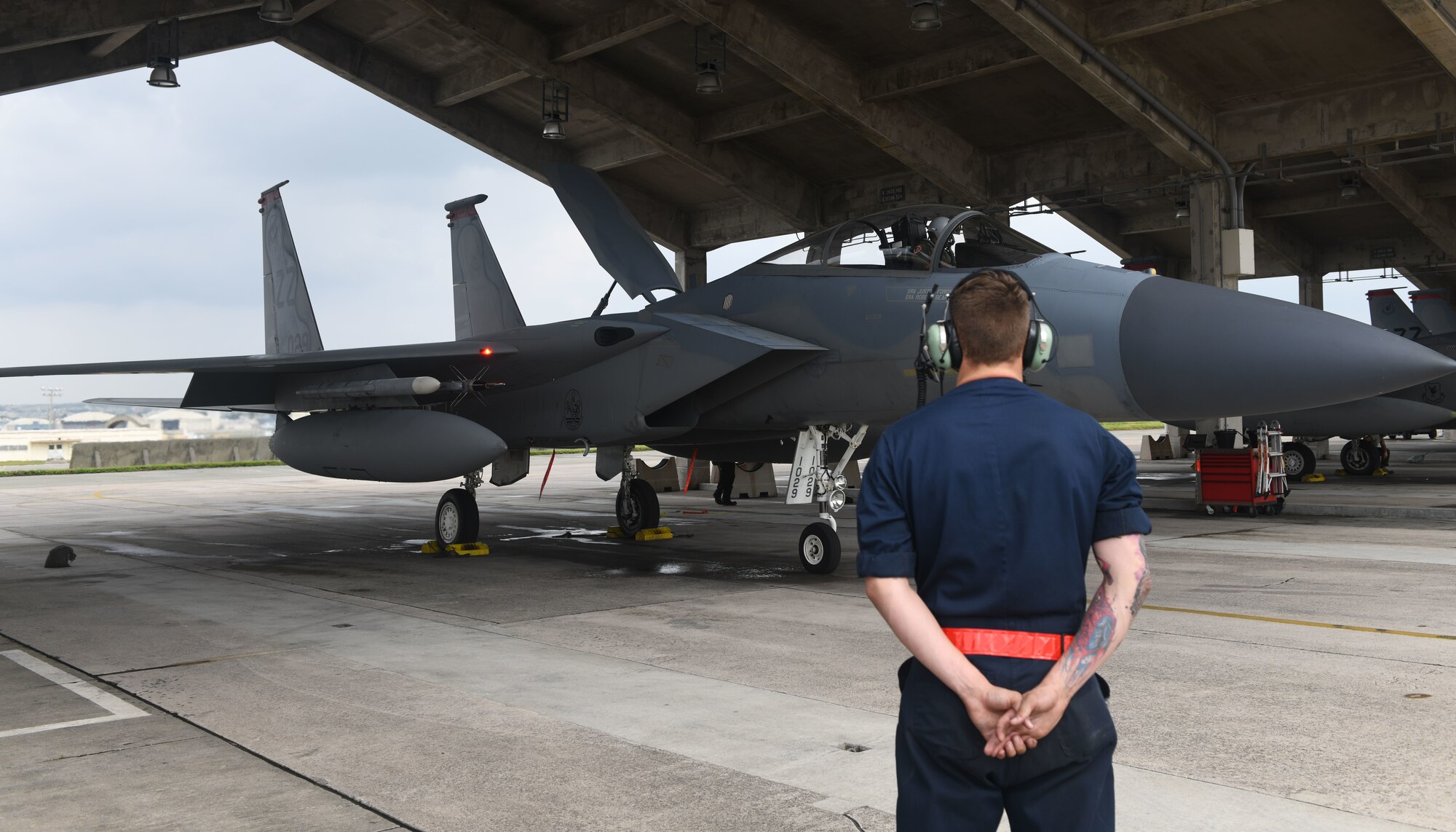 U.S Air Force Senior Airman Ryan Takacs, 18th Aircraft Maintenance Squadron crew chief, stands by before marshalling an F-15C Eagle during Exercise WestPac Rumrunner Oct. 16, 2020, at Kadena Air Base, Japan. Pacific Air Forces is validating new ways to deploy and maneuver assets in order to operate in contested environments through exercises, engagements and operations like WestPac Rumrunner. The 18th Wing-led exercise represents an evolution in the capabilities of 18th Wing assets to work with joint partners to defend American allies and ensure a free and open Indo-Pacific. (U.S. Air Force photo by Tech. Sgt. Benjamin Sutton)