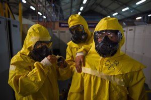 Photo of three Airmen securing their protective gear