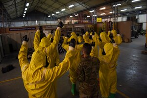 Photo of Airmen raising their hands in protective gear