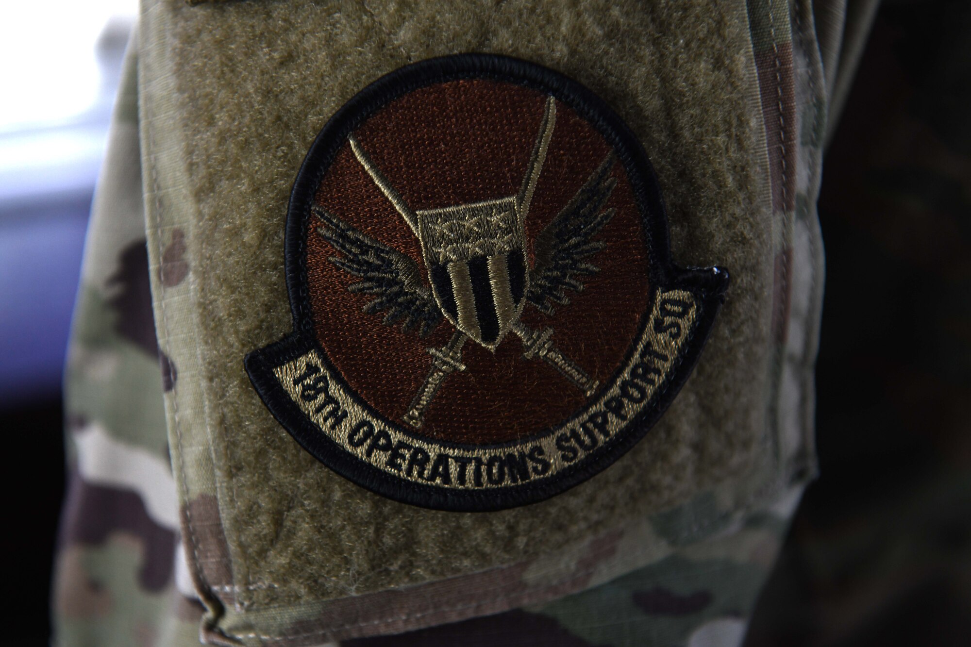 An Airman from the 18th Operations Support Squadron wears an 18th OSS patch during Exercise WestPac Rumrunner at Kadena Air Base, Japan, Oct. 16, 2020. The day-long exercise hailed several aircraft to include P-8s, F-16s and C-130Js; some coming all the way from Yokota and Misawa, as well as many home station aircraft – providing a number of training opportunities from the planning to the completion of the exercise. Kadena’s air traffic control tower utilizes training and experience in order to create an efficient and safe environment for the aircraft to depart and recover. (U.S. Air Force photo by Staff Sgt. Kristan Campbell)