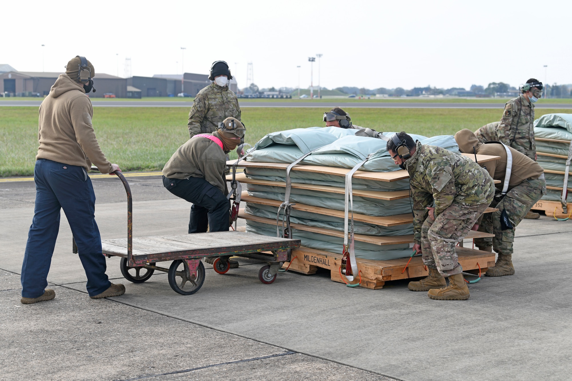 Airmen assigned to the 752nd Special Operations Aircraft Maintenance Squadron prepare to conduct emergency landing training with a CV-22 Osprey aircraft at Royal Air Force Mildenhall, England, Oct. 19, 2020. In the event of a landing gear malfunction, maintainers will guide the aircraft to land on a set of reinforced mattress pads to ensure the safety of both aircrew and aircraft. (U.S. Air Force photo by Staff. Sgt. Mackenzie Mendez)