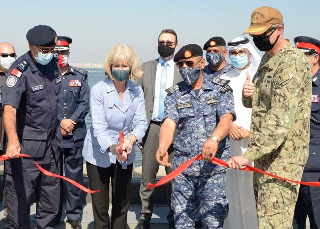 MANAMA, Bahrain (Oct. 21, 2020) Maggie Nardi, U.S. Embassy Chargé d’Affaires to the Kingdom of Bahrain, center, cuts a ribbon with Rear Adm. Curt Renshaw, deputy commander, U.S. Naval Forces Central Command, right, along with senior military and host nation leadership at a ceremony celebrating the installation of the coalition maritime forces waterfront security barrier at the Mina Salman Pier on board NSA Bahrain. The barrier is the first water-limited obstacle system security barrier system ever installed at an overseas naval installation, and the longest waterside security barrier in the U.S. Navy. NSA Bahrain enables the forward operations and responsiveness of U.S. and allied forces in support of Navy Region Europe, Africa, Central’s mission to provide services to the fleet, warfighter and family. (U.S. Navy photo by Mass Communication Specialist 1st Class Justin Yarborough)