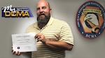 Man wearing a yellow-striped shirt holds a certificate