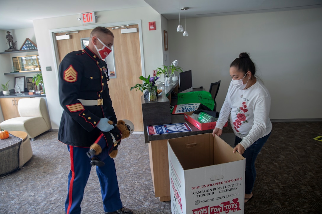 A Marine  prepares to drop a toy into a box.