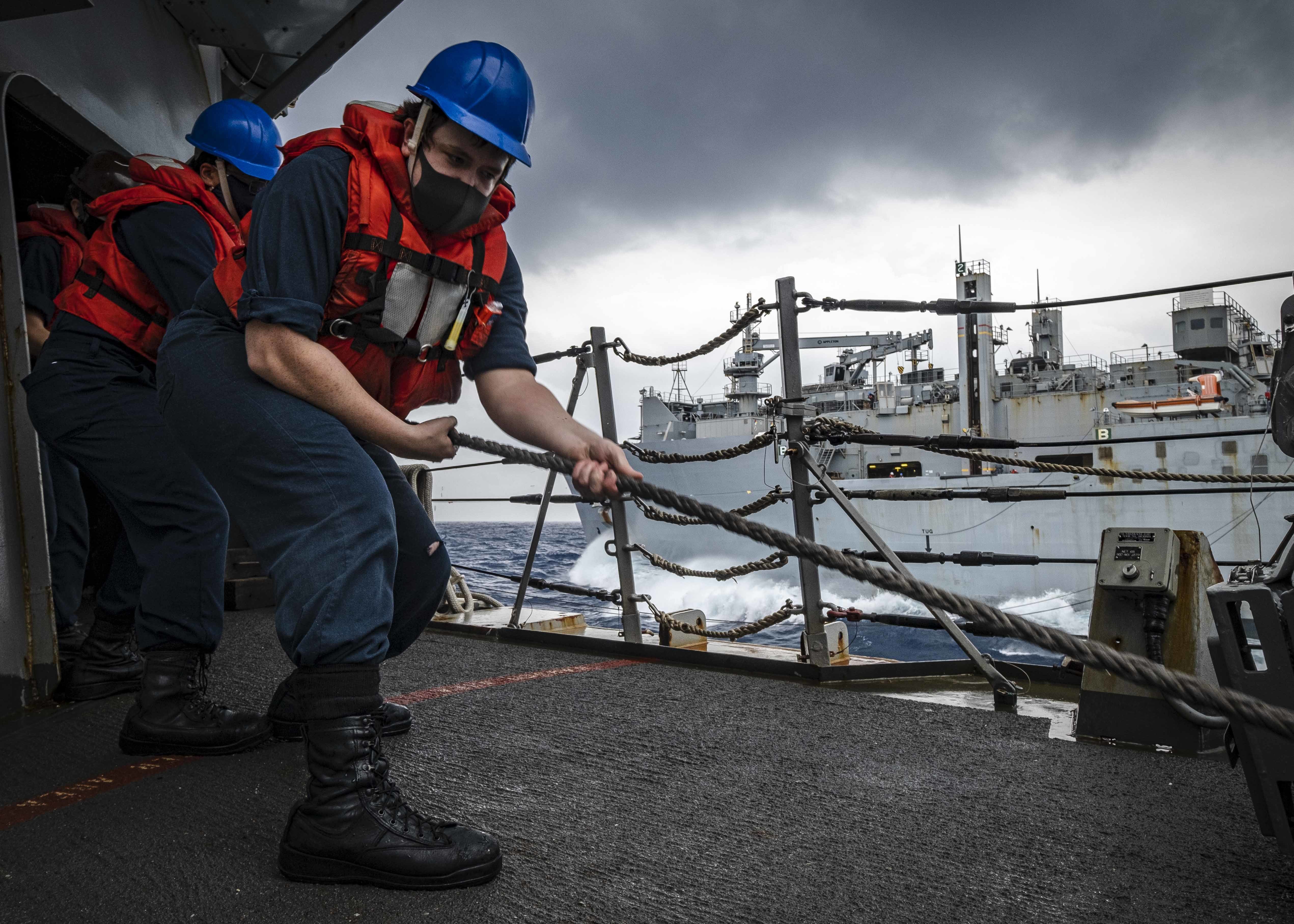 Sonar Technician (Surface) 3rd Class Tyler Allen, from Haysville, Kan., 'heaves' in a messenger line aboard USS John S. McCain (DDG 56) during a replenishment-at-sea