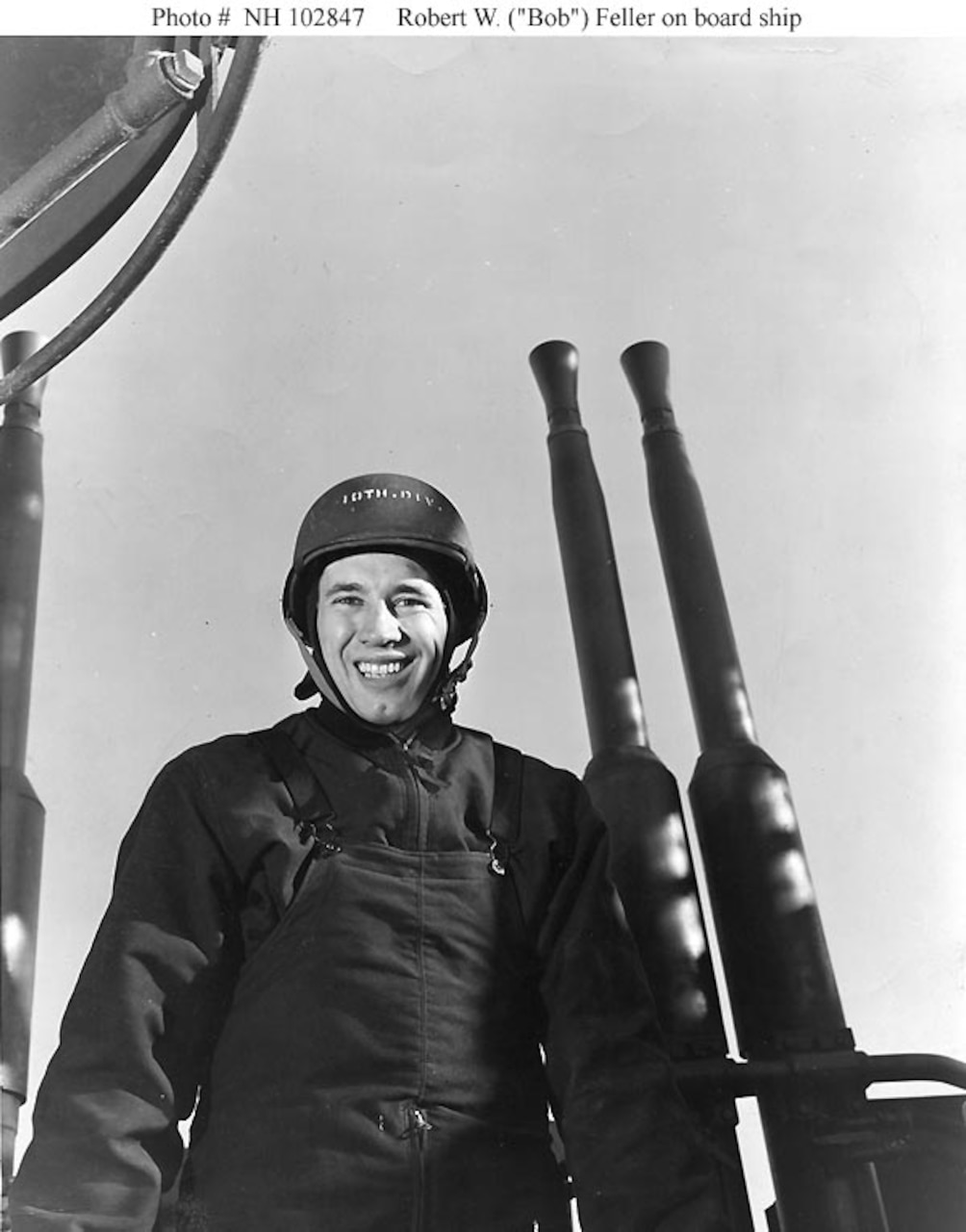 A sailor stands beside a gun.