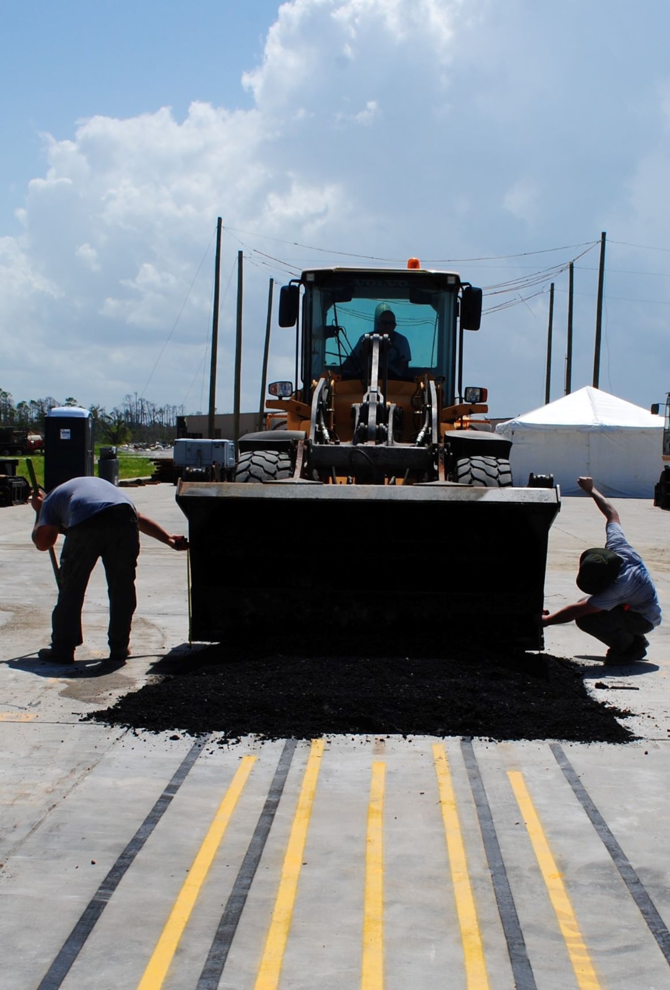 The Air Force Civil Engineer Center Lab research team place a hot-mix asphalt cap on top of the K-Fill CLSM backfill during field evaluations.