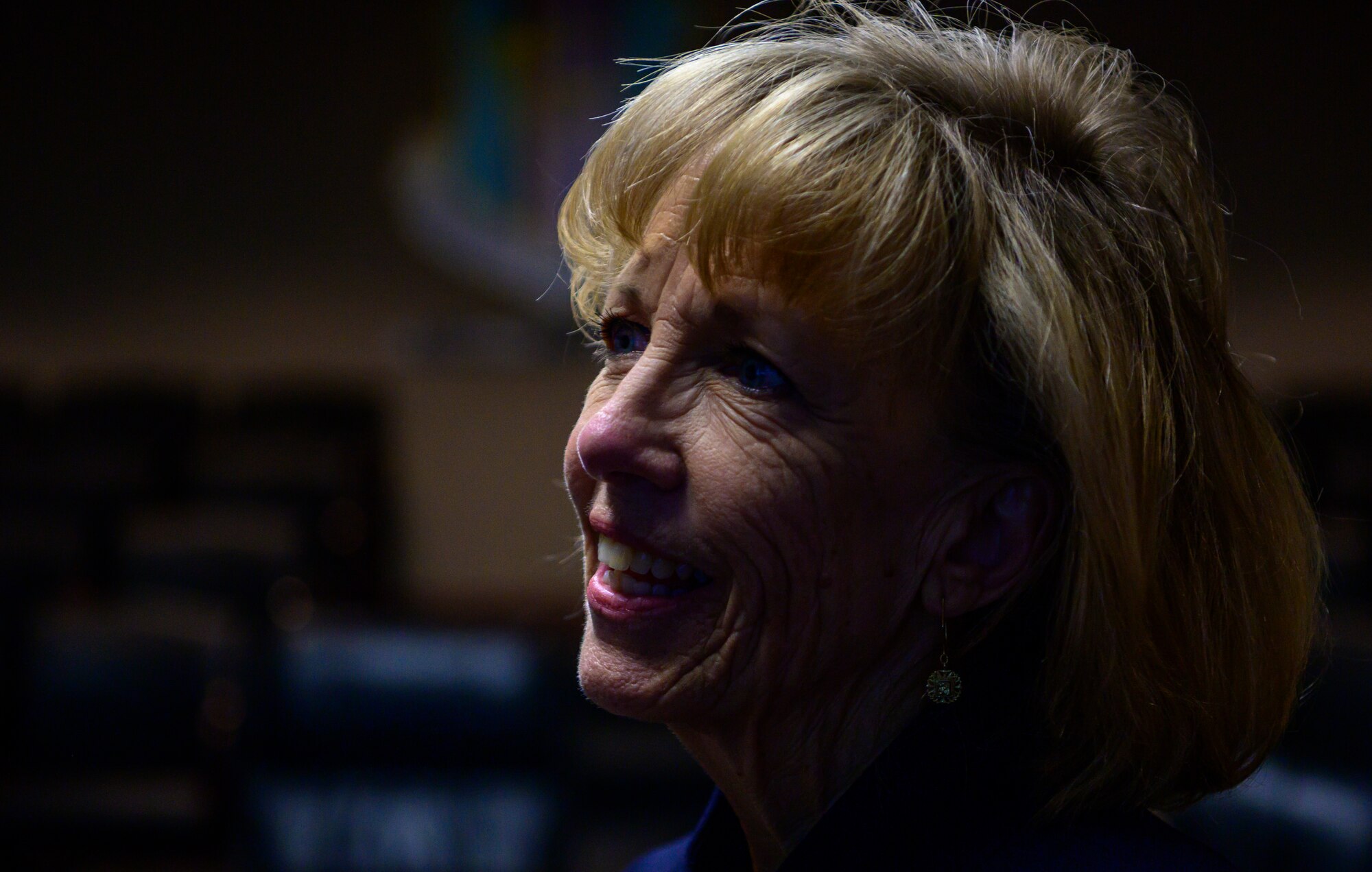 A portrait of a woman with blond hair and twinkles from the lights, in her eyes.