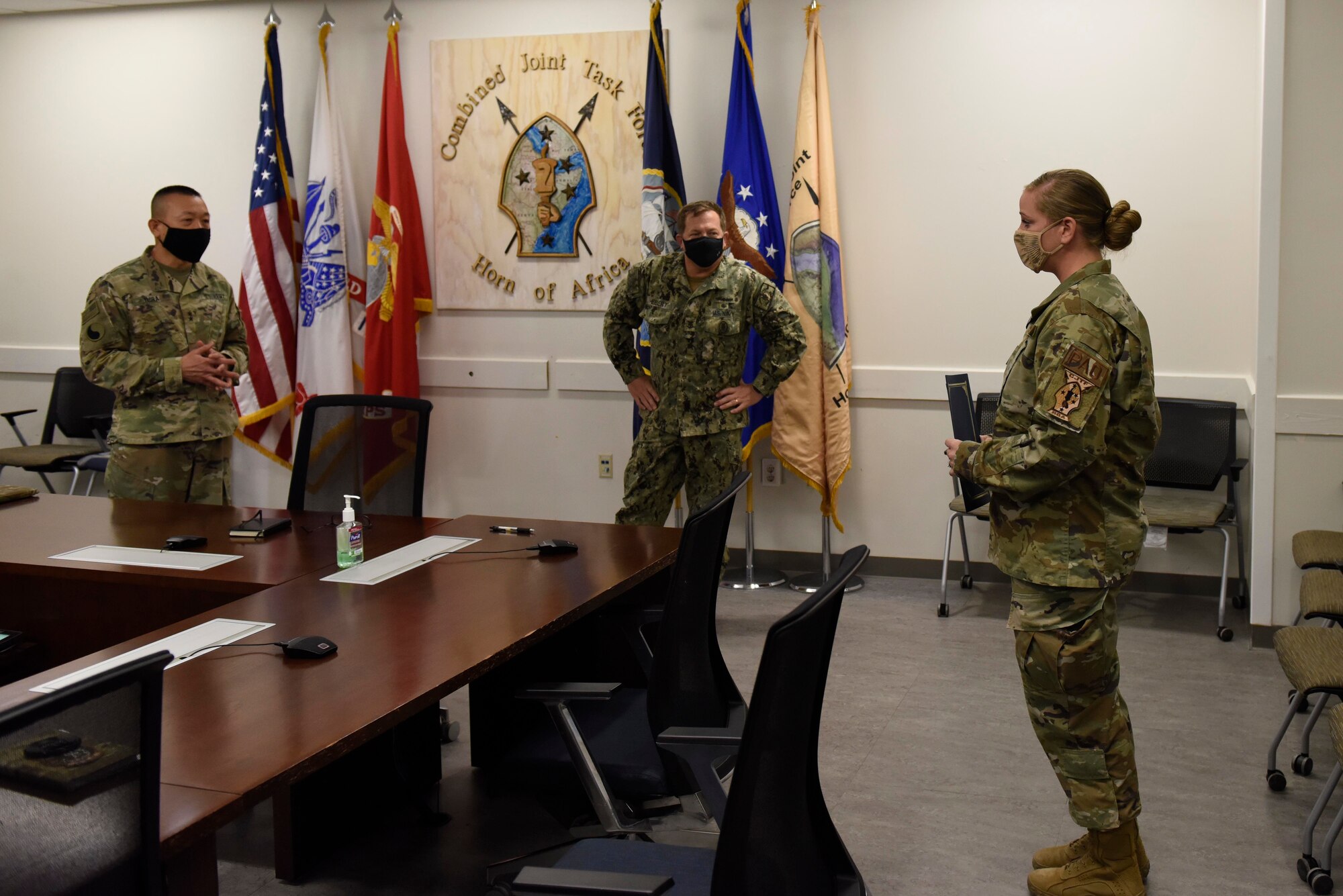 U.S. Army Maj. Gen. and  U.S. Navy Command Master Chief Petty Officer stand in front Tech. Sgt. to congratulate her