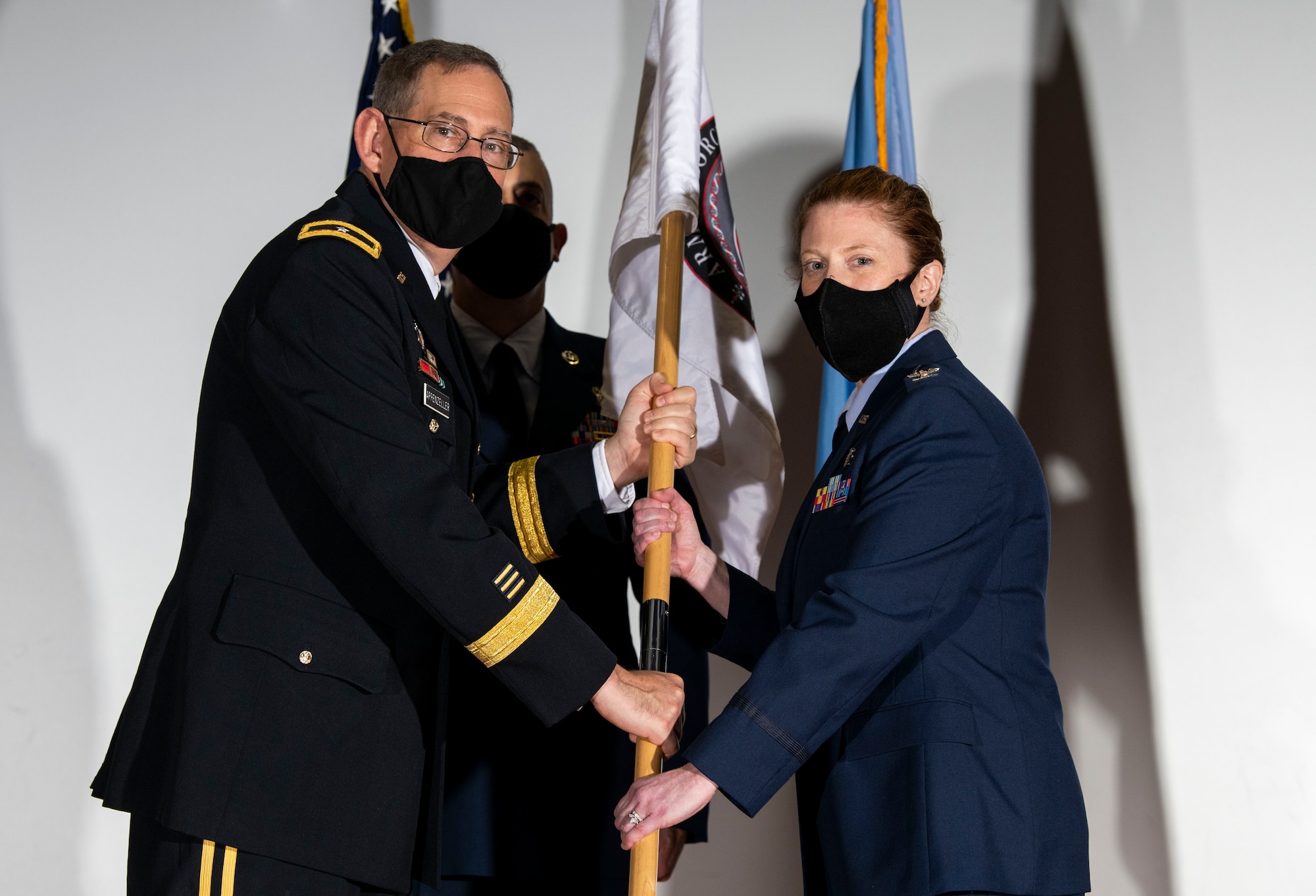 U.S. Army Brig. Gen. George Appenzeller (left), Defense Health Agency assistant director, presents the Armed Forces Medical Examiner System guidon to U.S. Air Force Col. Alice Briones, incoming AFMES director, during a change of directorship ceremony at Dover Air Force Base, Delaware, Oct. 21, 2020. AFMES provides the Department of Defense and other federal agencies comprehensive forensic investigative services, to include forensic pathology, DNA forensics, forensic toxicology and medical mortality surveillance. (U.S. Air Force photo by Senior Airman Christopher Quail)