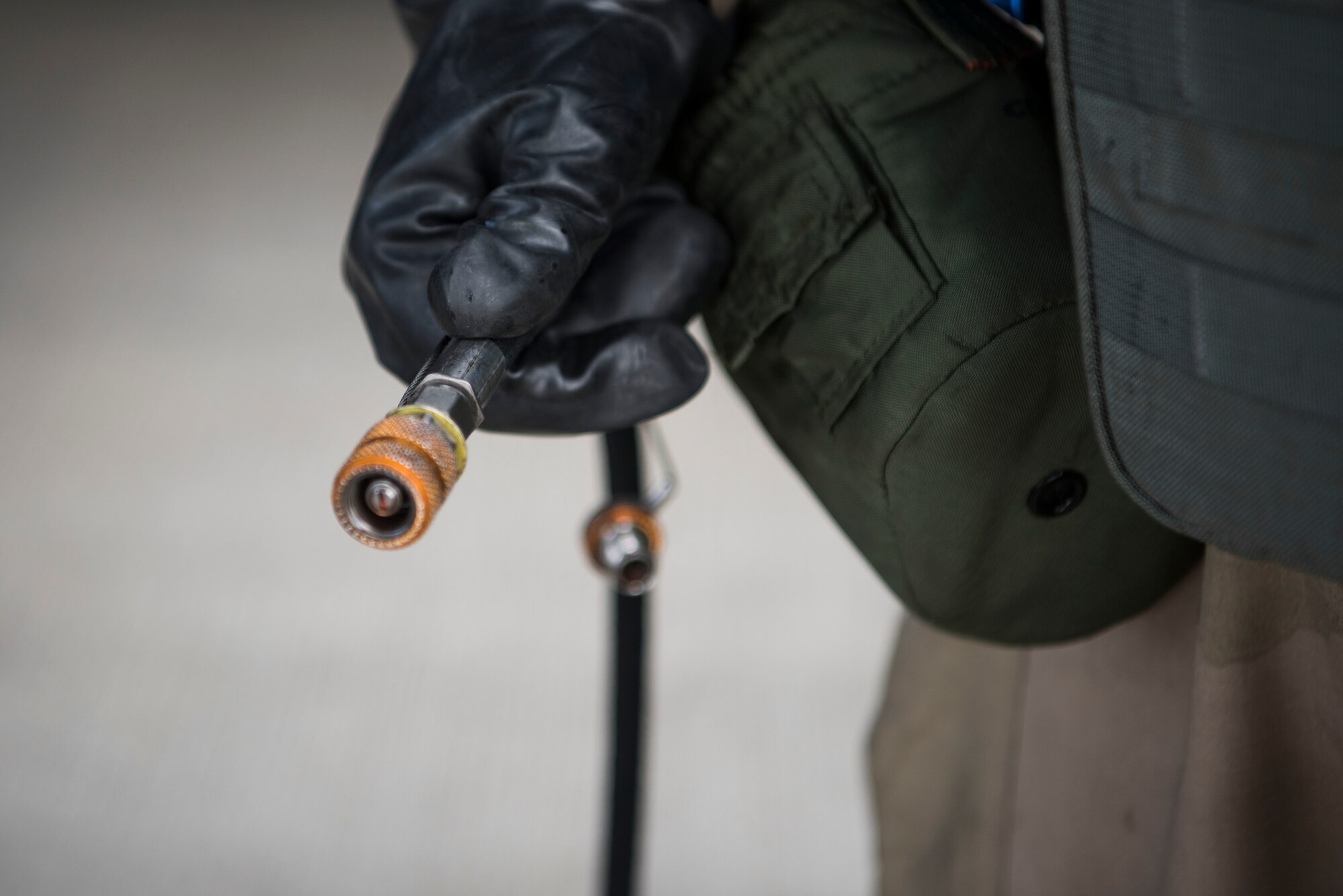 A U.S. Air Force Airman assigned to the 721st Aircraft Maintenance Squadron holds an air compressor hose on the flightline during exercise Nodal Lightning 20-2