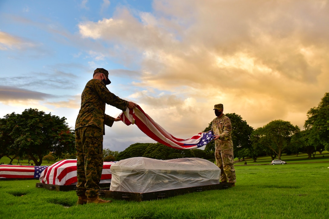 A Marine and a soldier place an American flag on a casket.