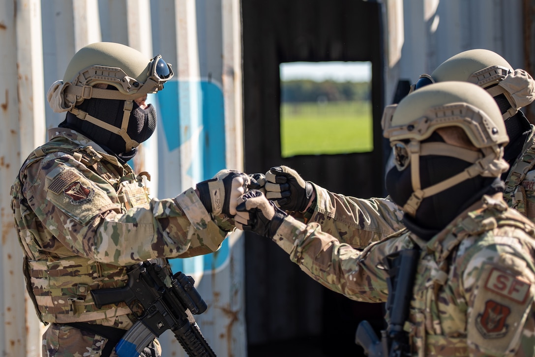 Three airmen bump fists.