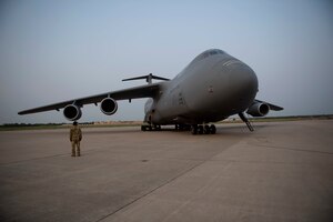 A man can be seen in front of a C-5, a very large aircraft.