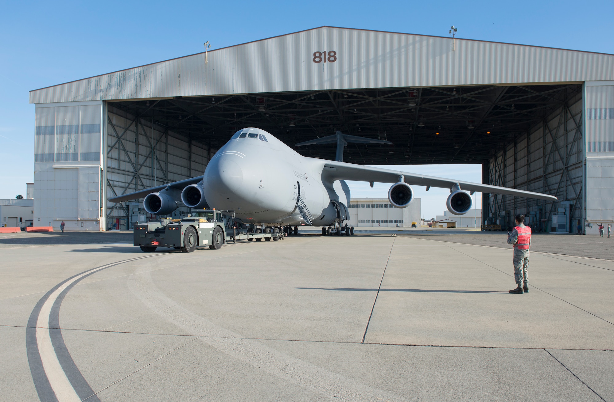 A man stands in front of a C-5, a very large aircraft.