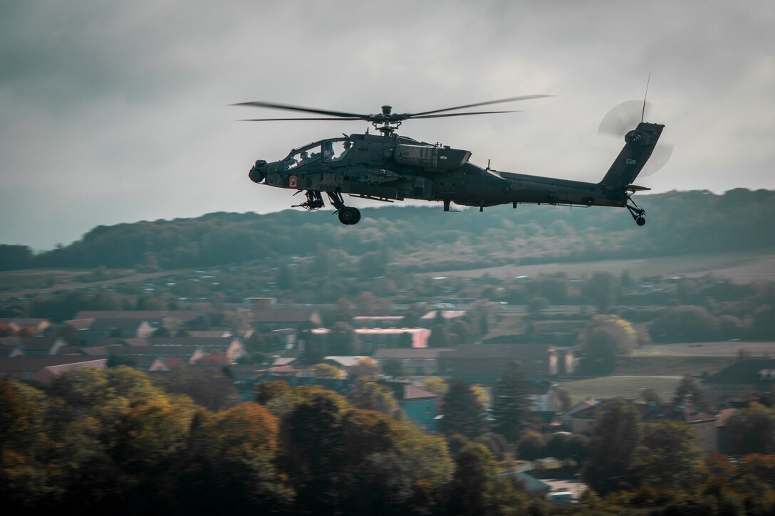 An Apache helicopter flies over town.