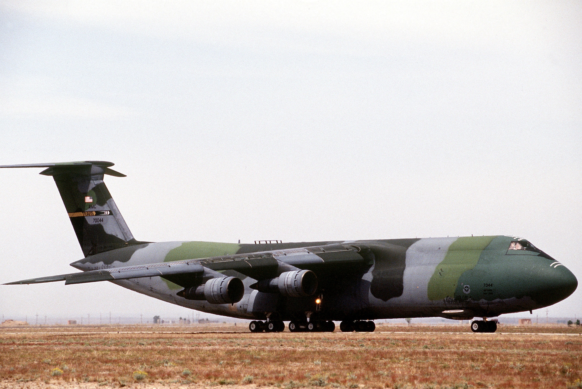A C-5 with camo painting is seen driving down the flight line.
