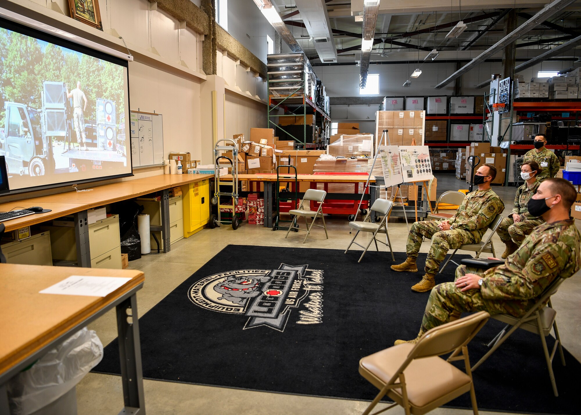 Individuals sit to watch a briefing.