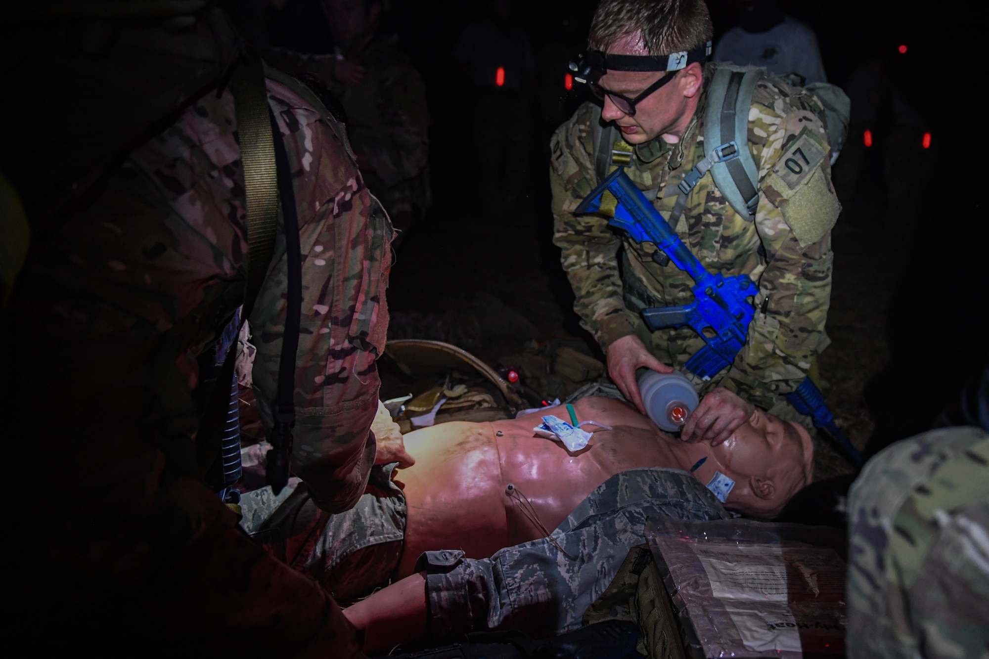 Special Operations Surgical Team candidates participate in a medical scenario operating on a subject in low light