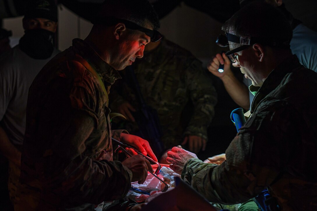 Special Operations Surgical Team candidates participate in a medical scenario operating on a subject in low light