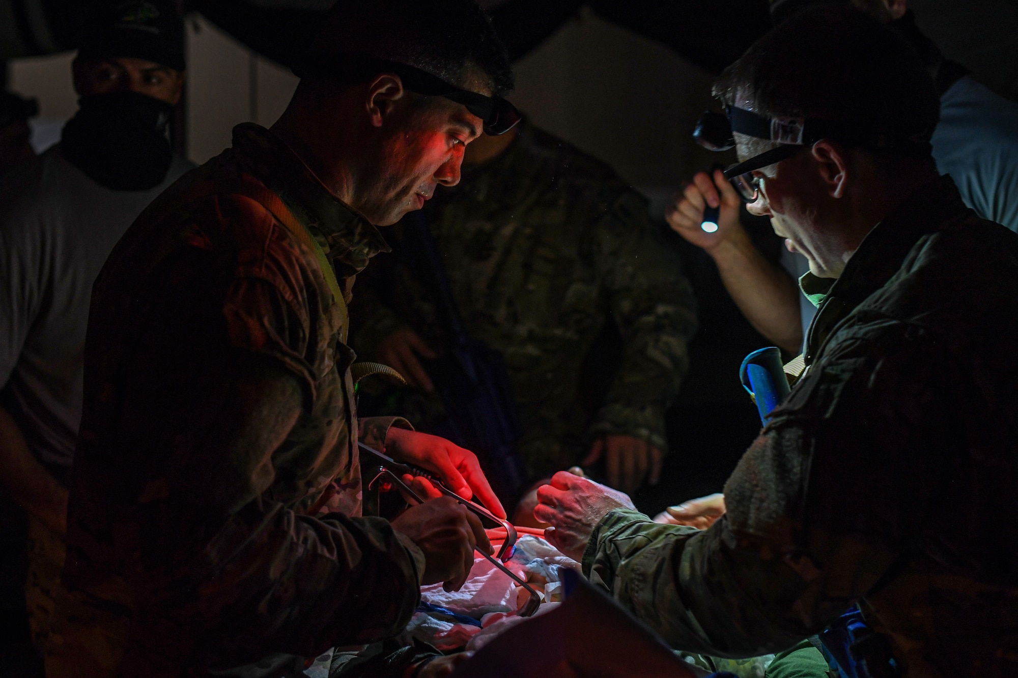 Special Operations Surgical Team candidates participate in a medical scenario operating on a subject in low light