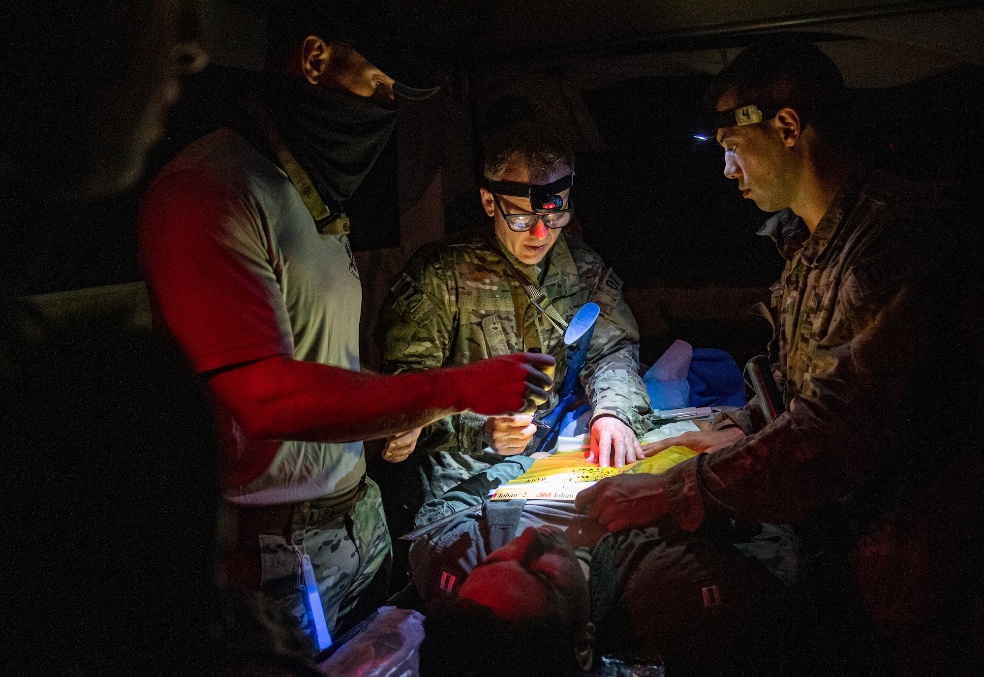 Special Operations Surgical Team candidates participate in a medical scenario operating in low light.