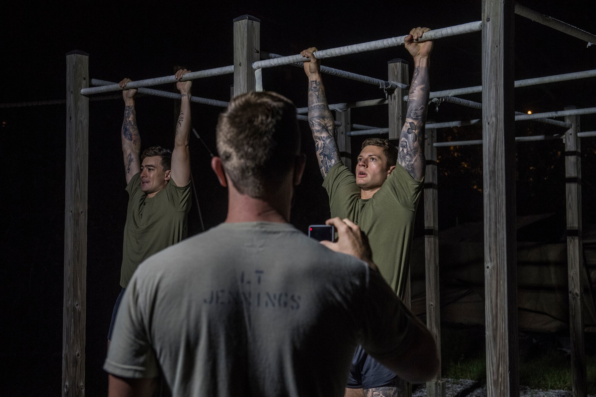A pair of Special Tactics tactical air control party candidates hang from pull up bars during testing.