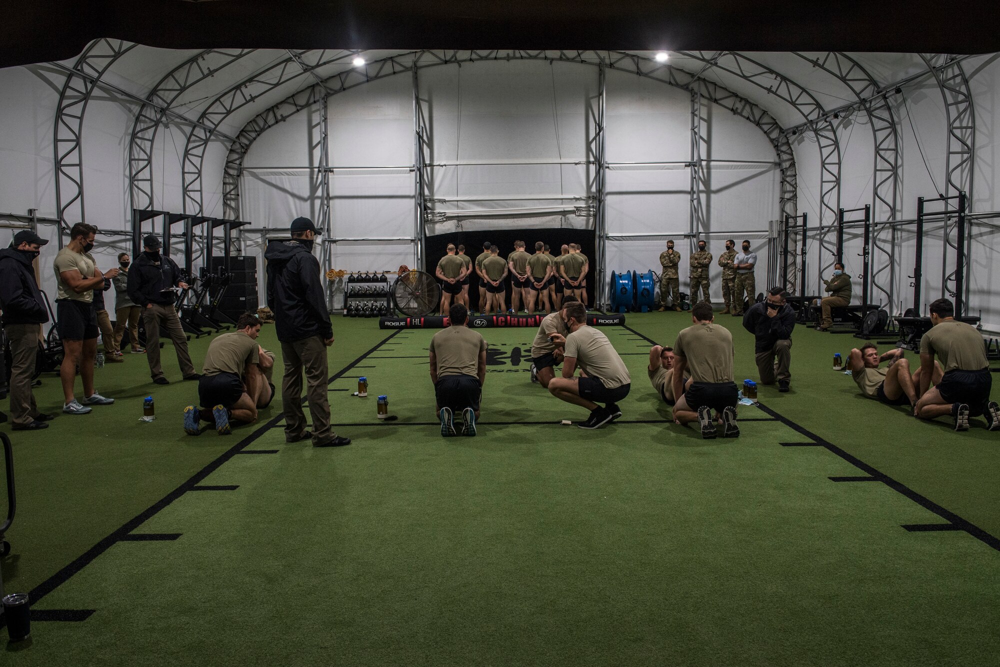 Four pairs of Special Tactics tactical air control party candidates conduct a physical fitness test during an assessment. One set of candidates hold the feet of other candidates performing sit-ups.