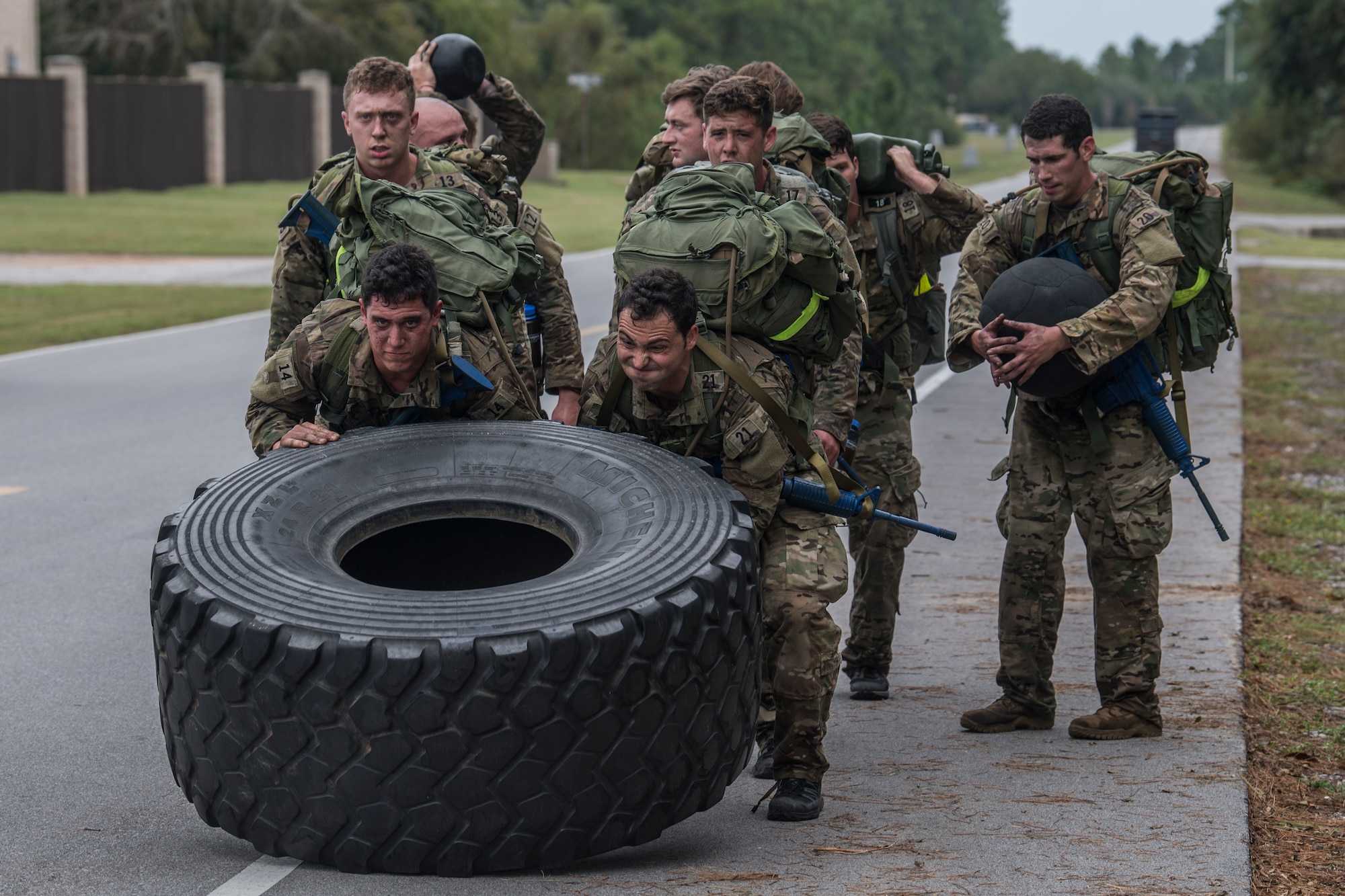 A pair of Special Tactics tactical air control party candidates flip a tire about 4 feet in diameter and about 2 feet thick during an assessment and selection process