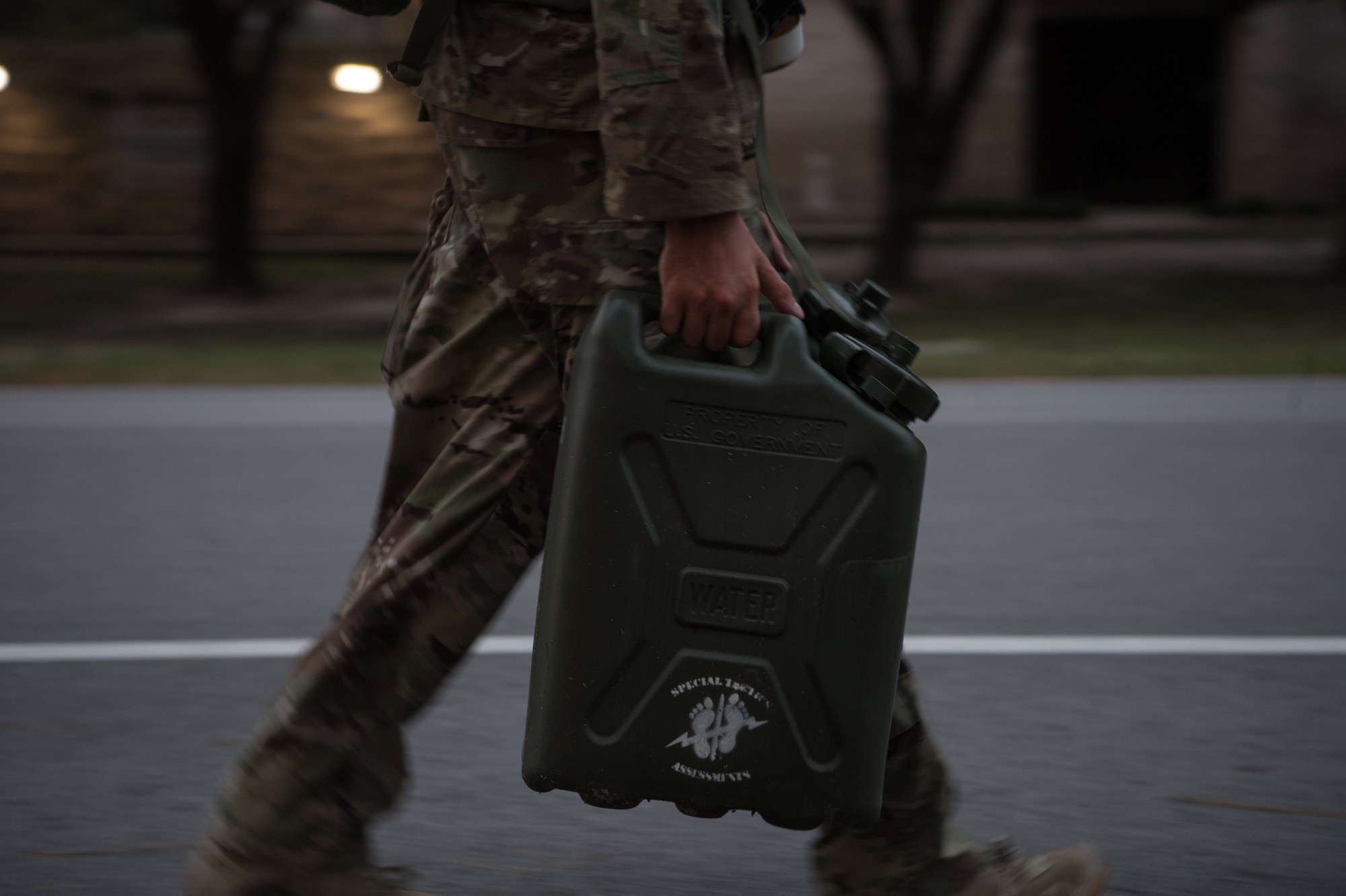 A lone Special Tactics tactical air control party candidate carries a jerry can of water as part of his assessment