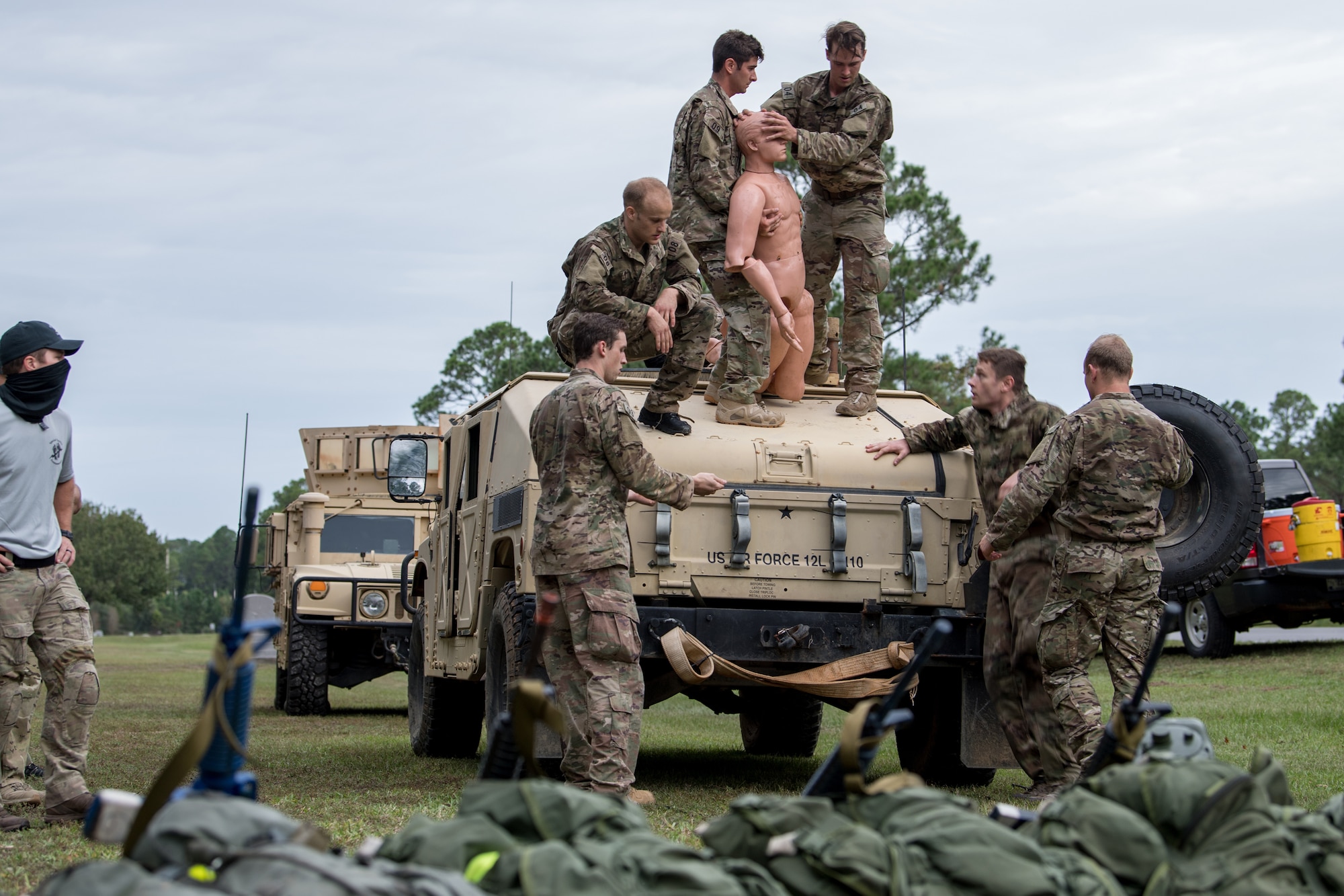 Special Tactics tactical air control party candidates rescue a simulated patient from a Humvee. Several candidates are standing on the roof of the Humvee with the mannequin between them. Others stand around the Humvee.