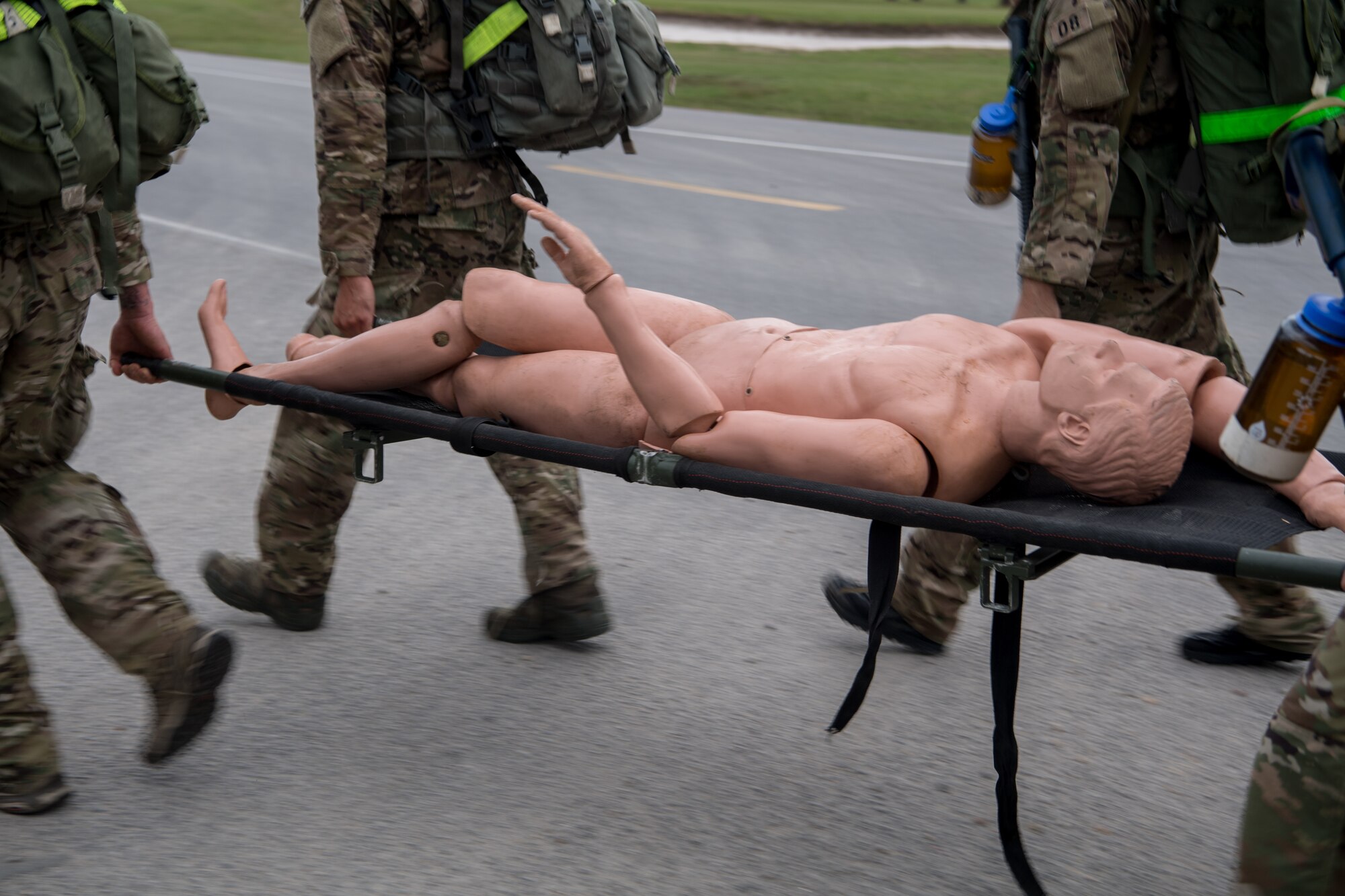 Four Special Tactics tactical air control party candidates carry a mannequin patient on a litter down a road as part of scenario during assessment