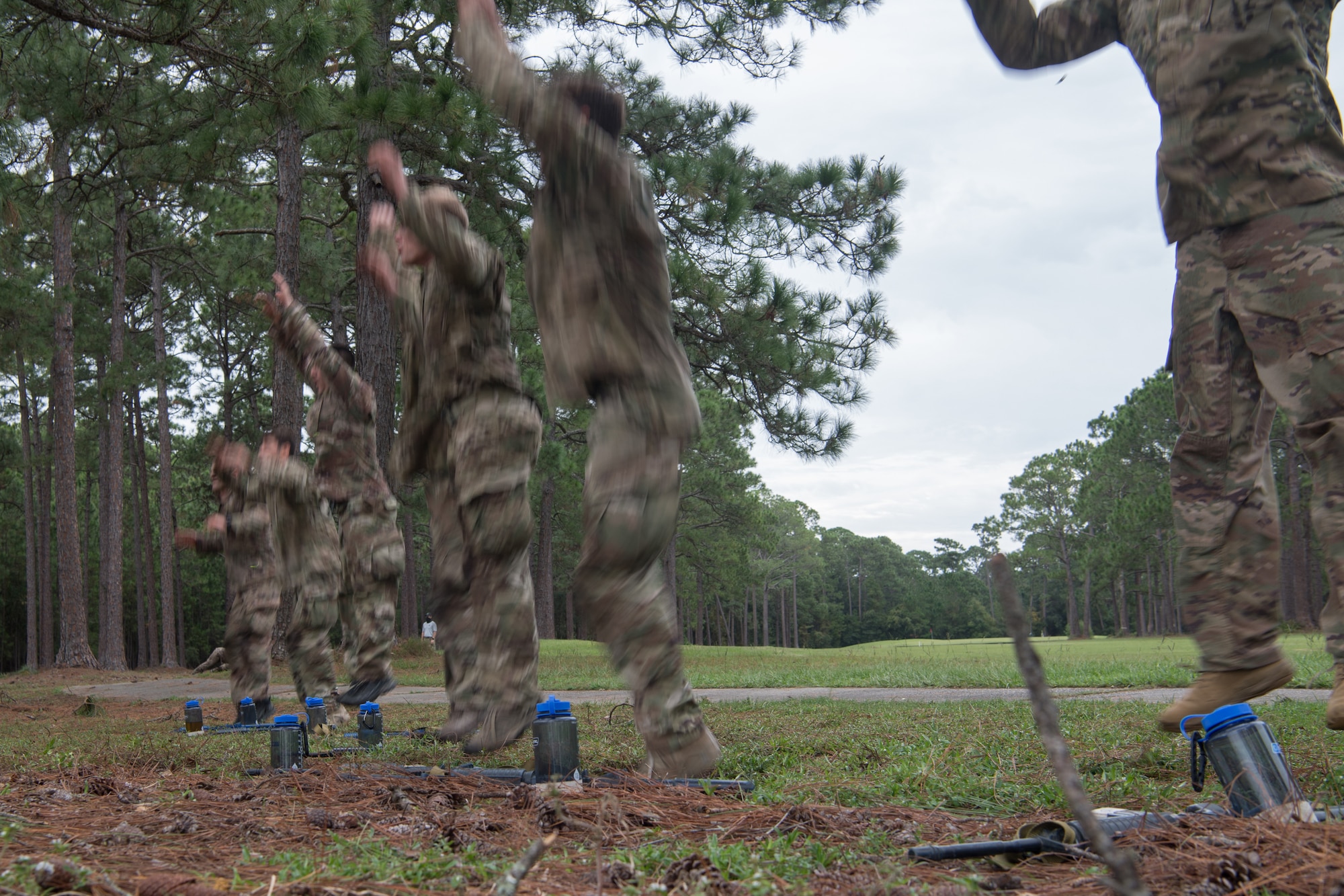 Special Tactics tactical air control party candidates all jump into the air with their hands above their heads all at the same time while in a line.