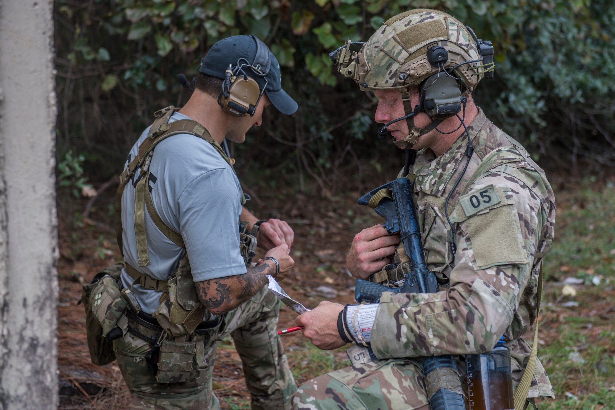 A pair of tactical air control party candidates participate in a call for fire scenario by facing each other and talking into headsets connected to radios on their vests.