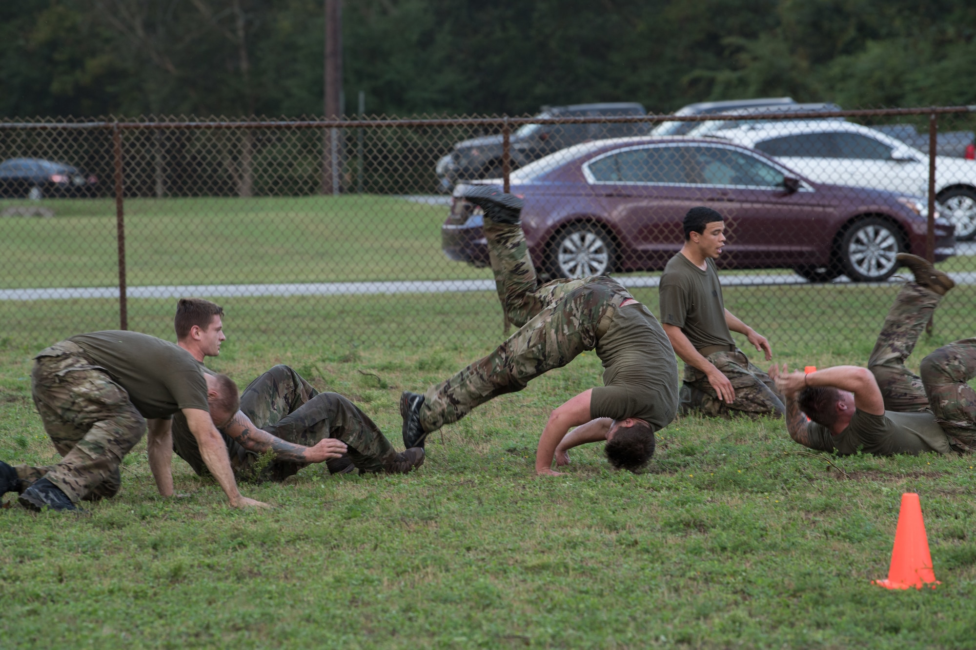 Special Tactics tactical air control party candidates perform forward somersaults as they roll forward across the grass field.