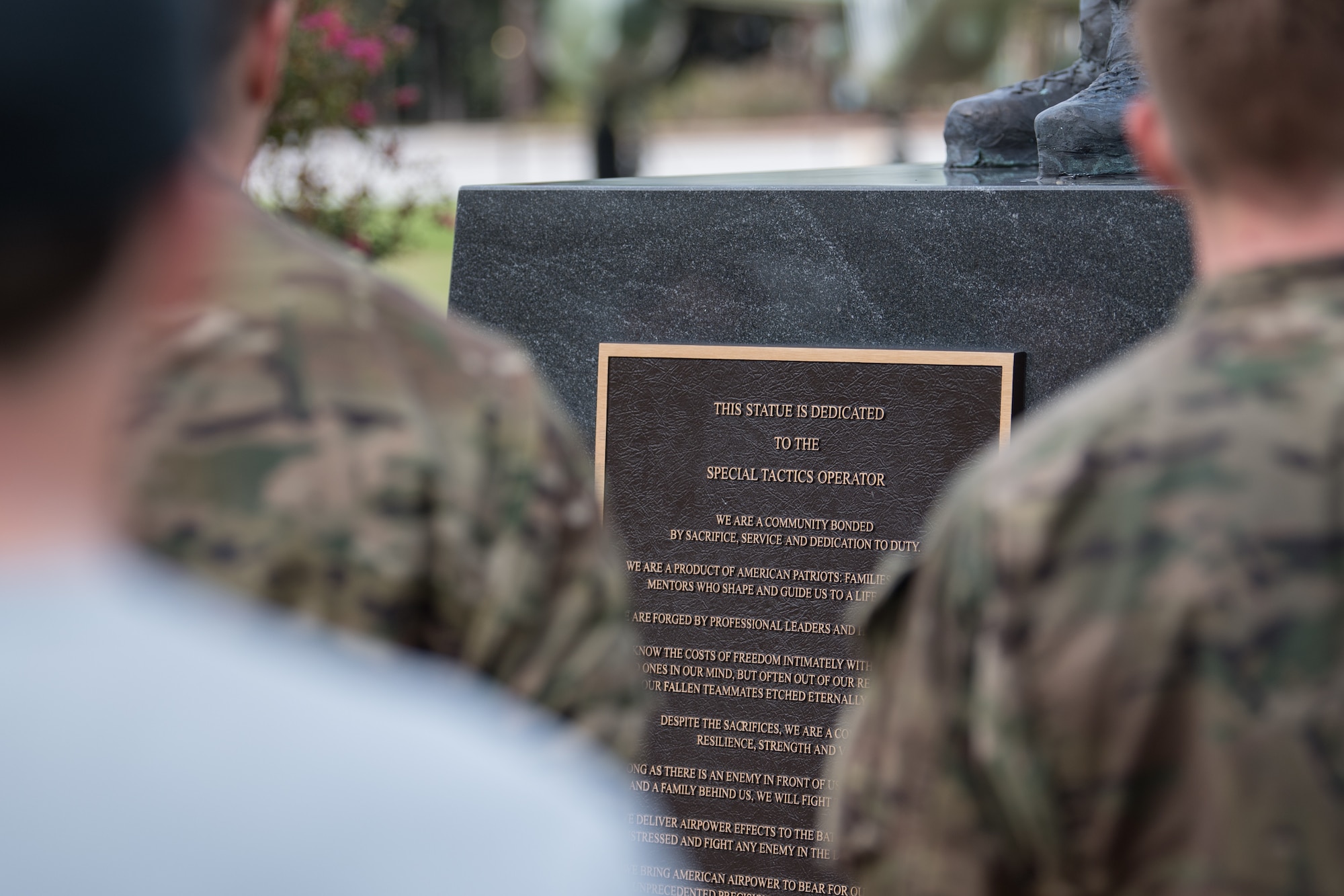 We stand looking over the shoulders of a few Special Tactics tactical air control party candidates looking at a plaque on a memorial.