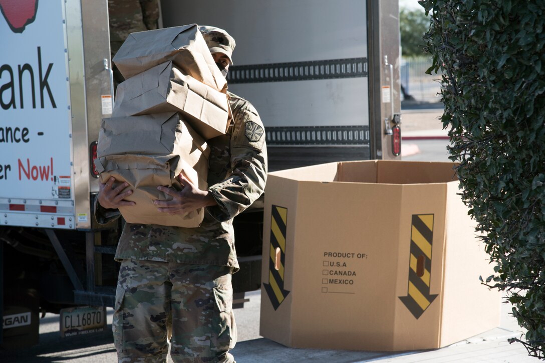 A guardsman carries boxes of food.