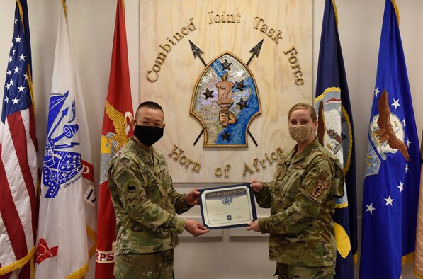 U.S. Army Maj. Gen. Lapthe C. Flora stands to the left presenting a promotion certificate to  U.S. Air Force Tech. Sgt. Dana Cable standing on the right