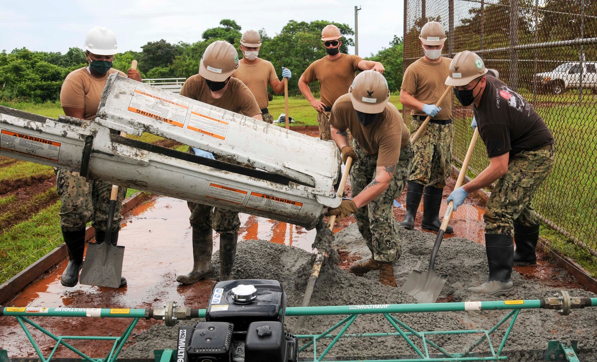 Sailors from Naval Facilities Engineering Command (NAVFAC) Marianas and Naval Mobile Construction Battalion 133 pour and lay a cement foundation during a community relations project at Okkodo High School in Dededo.