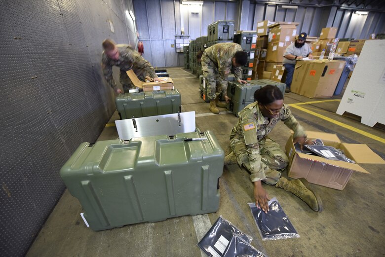 Military personnel handle goods in a warehouse.