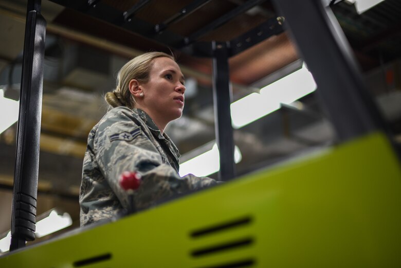 A service member uniform drives a forklift.
