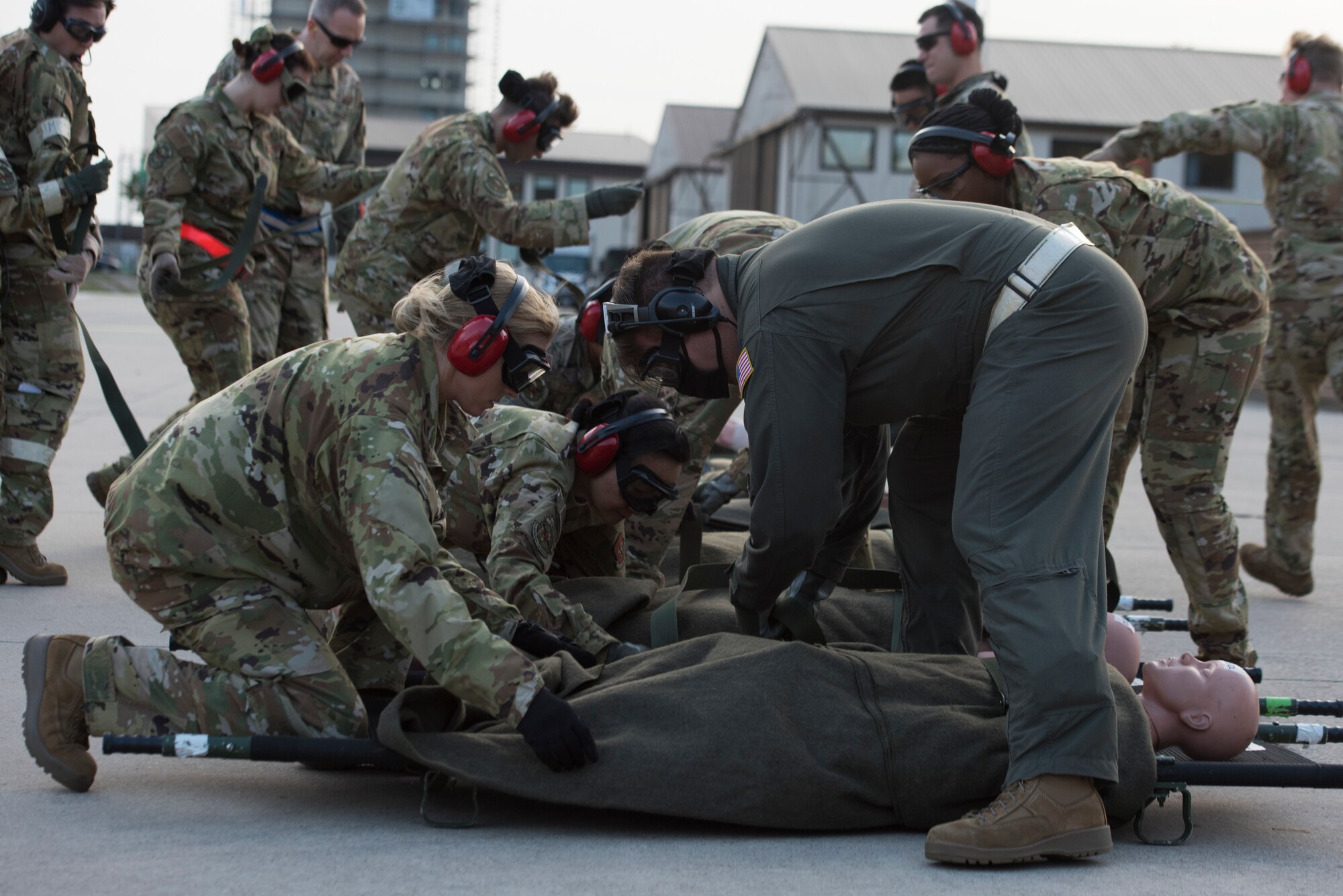 Airmen secure simulated victims to stretchers.