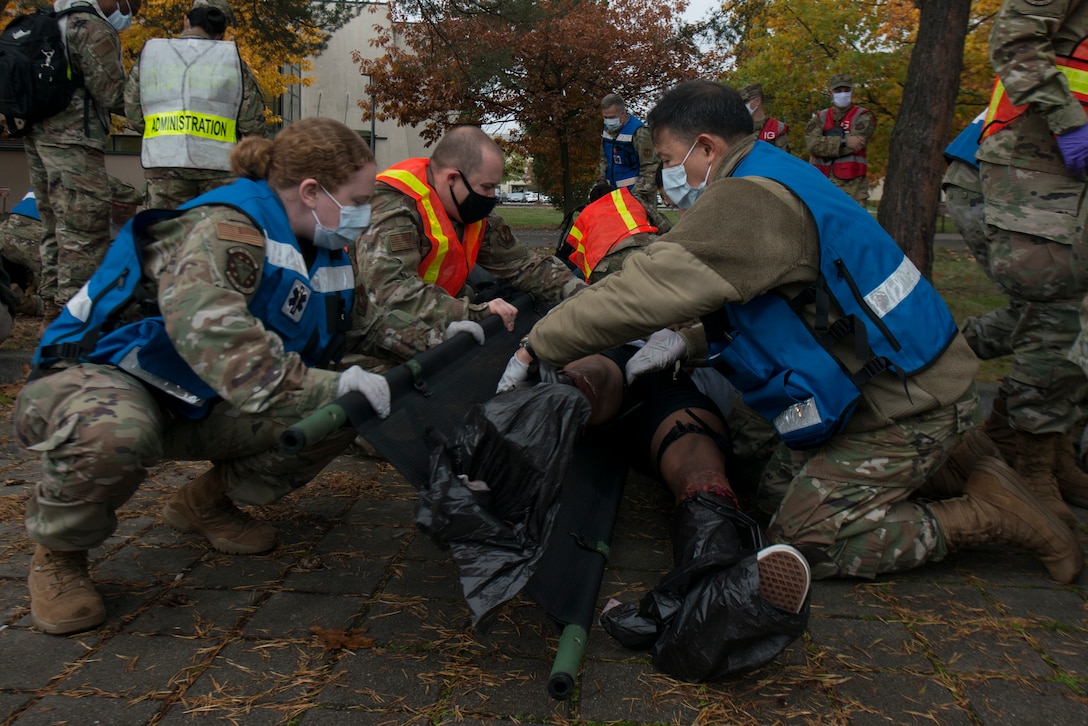 Medical Airmen transfer a simulated victim to a stretcher.
