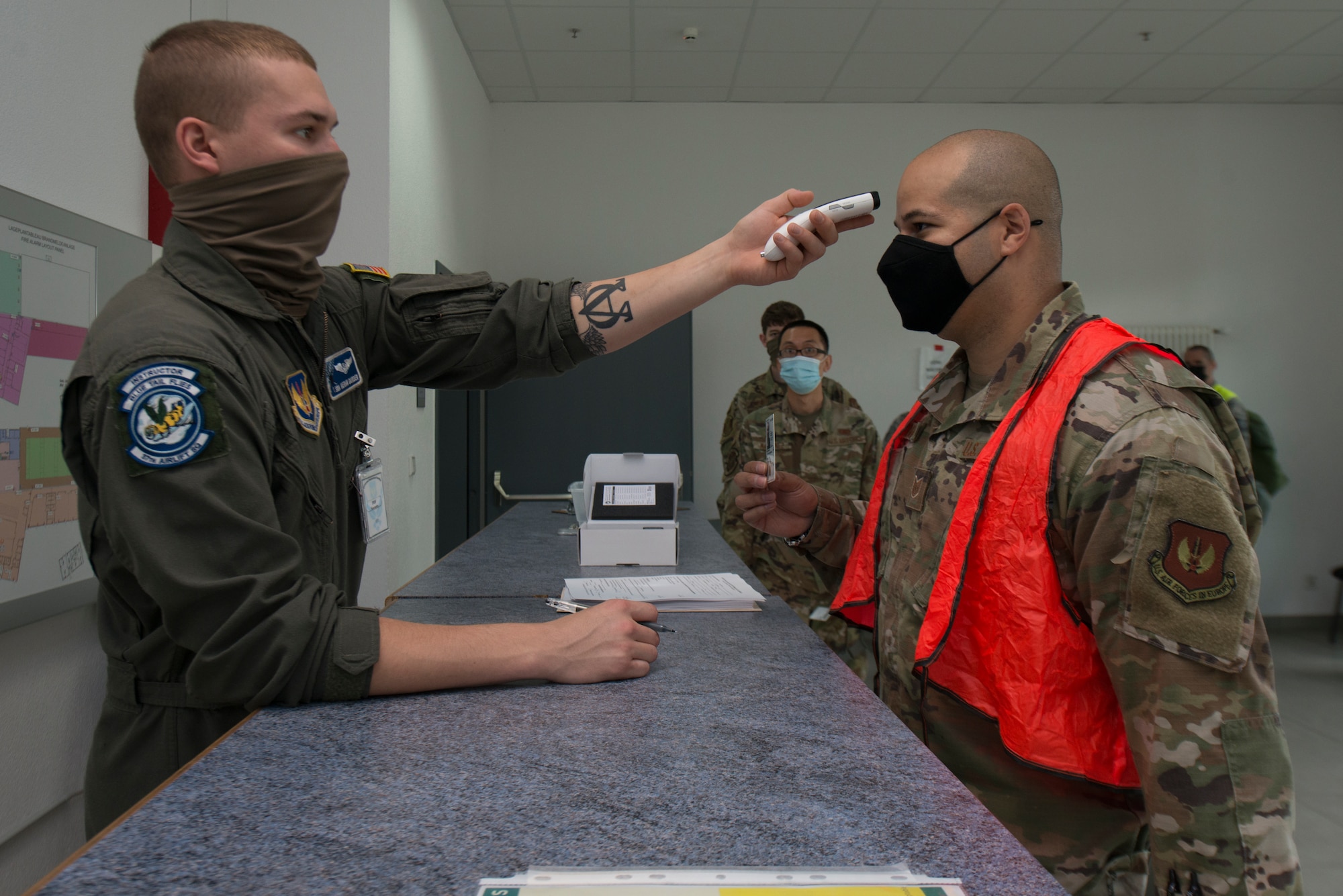 An Airman measures the temperature of another Airman.