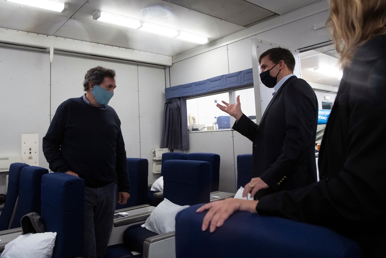 Defense Secretary Dr. Mark T. Esper speaks to people on a plane.