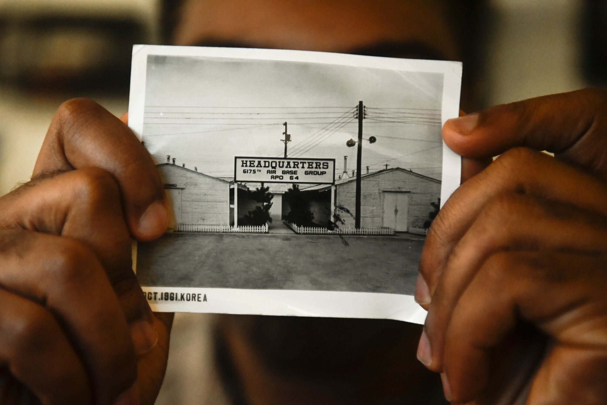 A photo of an Airman holding an old photo from the 1960s.